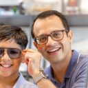 Indian father and son choosing eyeglasses in optics store