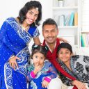 Portrait of Asian Indian family at home, happy parents and children in traditional sari.