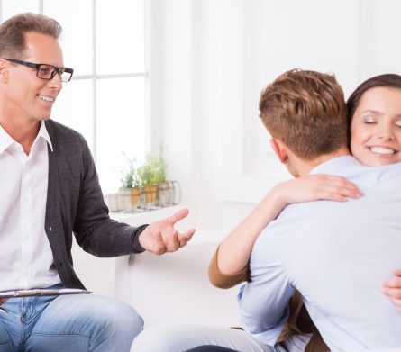Together again. Happy young couple hugging while sitting together with psychiatrist