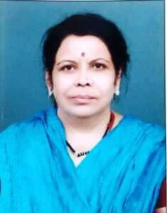 Portrait of a woman with short dark hair wearing a blue saree and a small red bindi against a blue background
